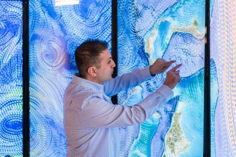 Erol Aygar conducts data visualization research at the Center for Coastal and Ocean Mapping in Durham for his master's thesis using a giant colorful screen wall projection.